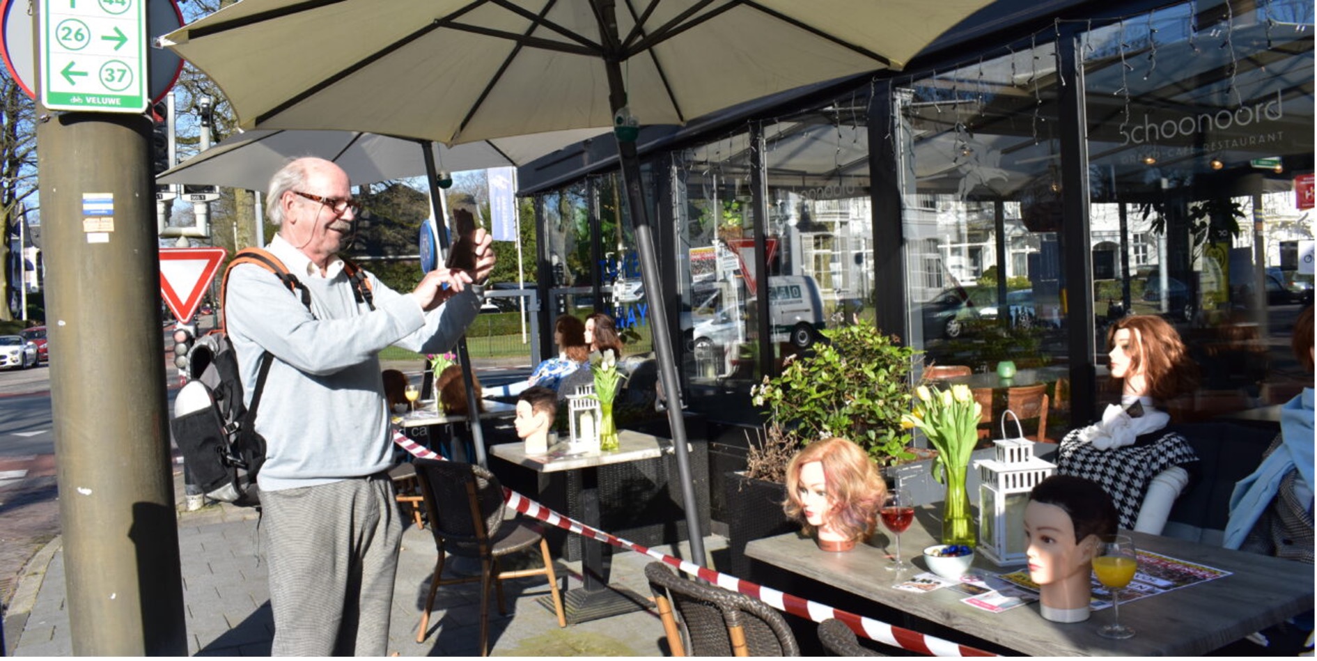 Voorbijganger fotografeert poppen op het terras van restaurant Schoonoord.