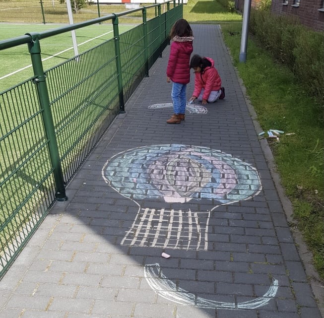 Refugee children drawing on the ground with chalk
