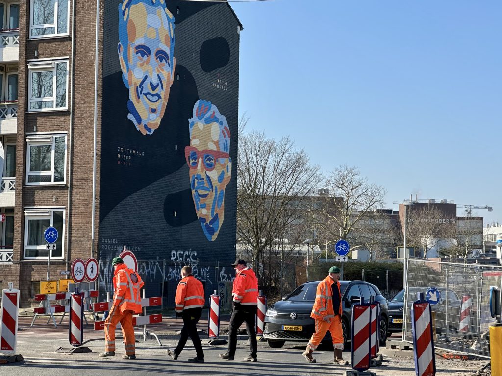 Construction workers walking in front of the mural.