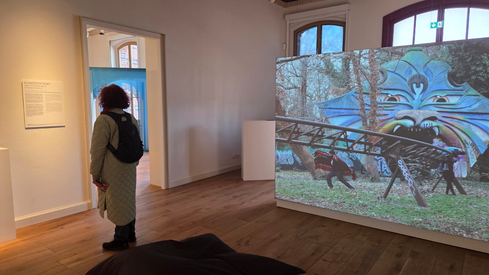 Visitor at the exhibition standing in front of a video installation showing a former ride and choreographic scores recorded by the group “Flower Foundry”.
