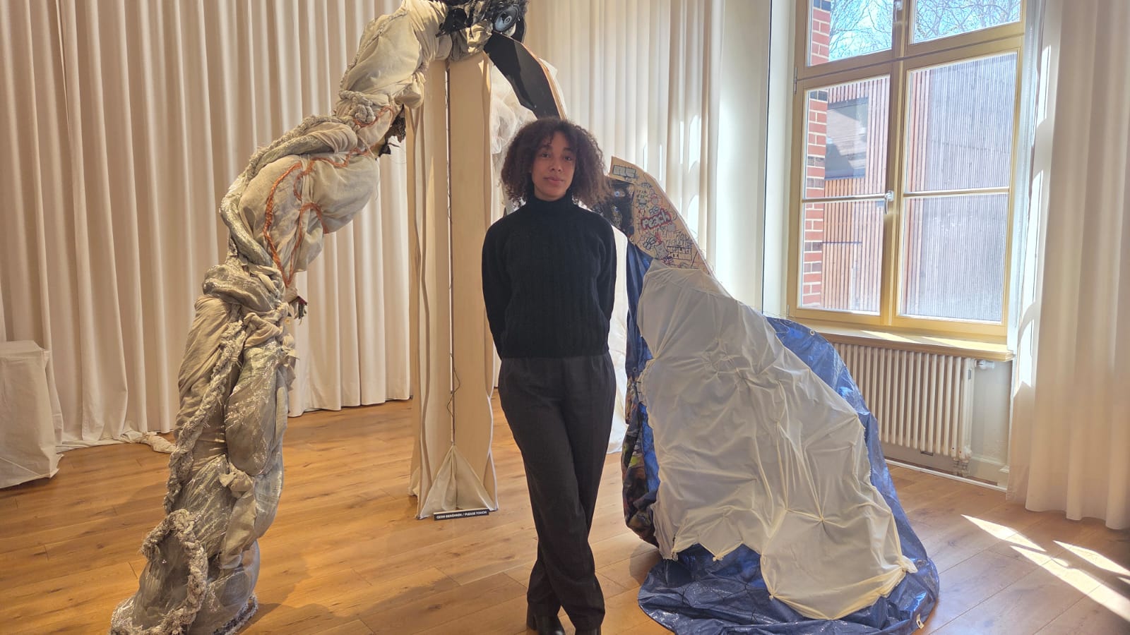 Curator Temitayo Oni in front of the artwork "Desire Lines" - a multisensory installation composed of various textiles and materials that echo plant life and mandmade elements found in Spreepark.